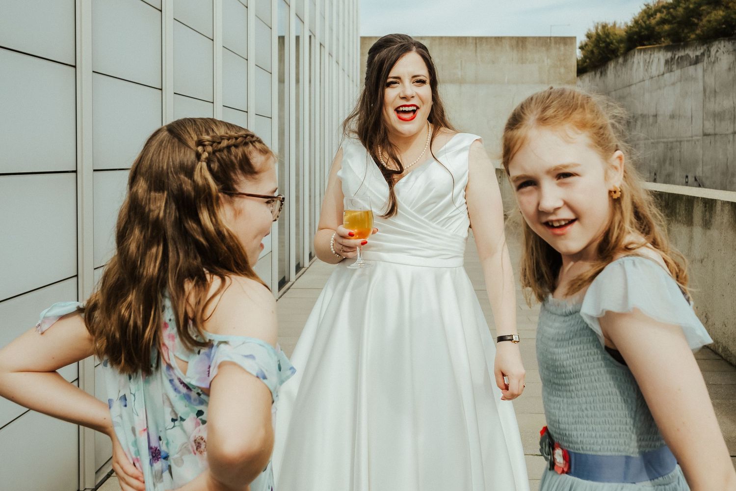 Three women sharing a cheerful moment at an outdoor wedding celebration.