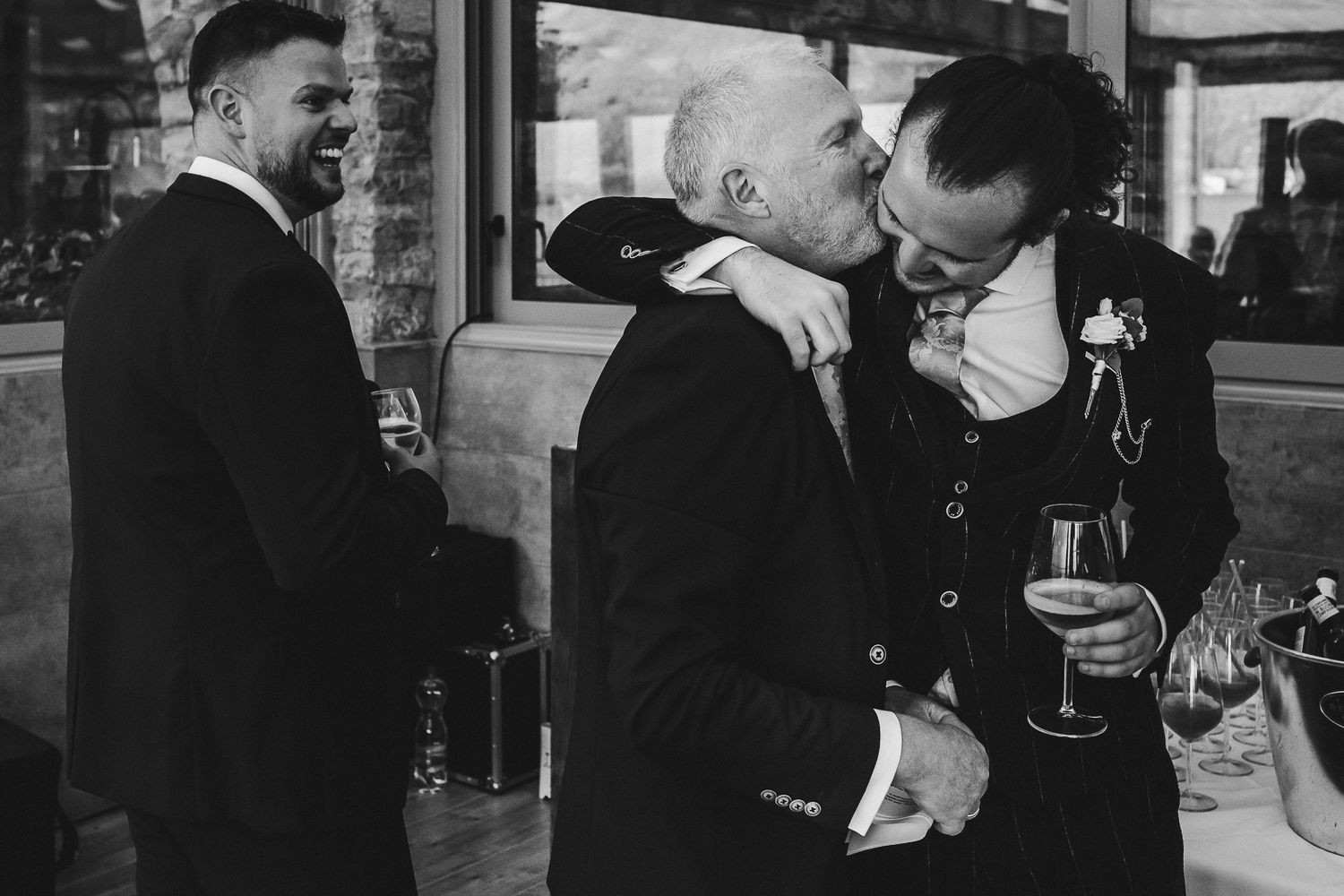 A black and white capture of emotional embraces during wedding celebrations.
