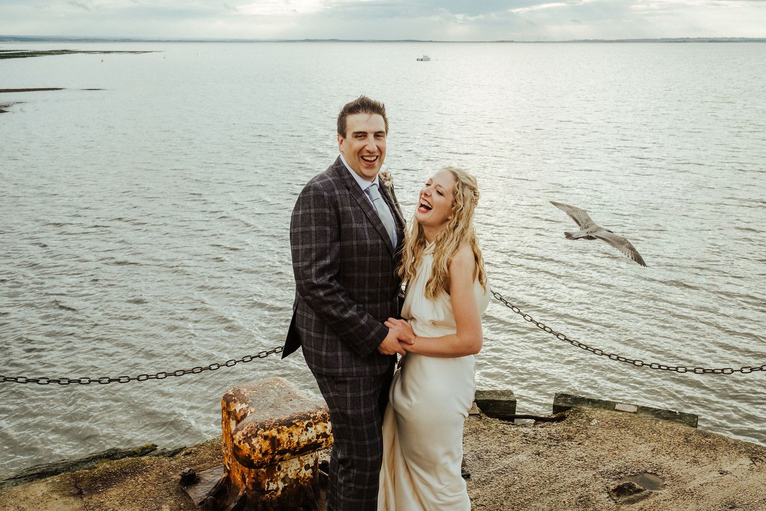 Romantic waterfront wedding photoshoot with couple against serene ocean backdrop.