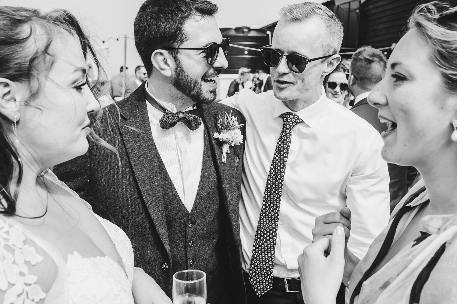 Black and white candid shot of wedding guests sharing laughs during the reception.
