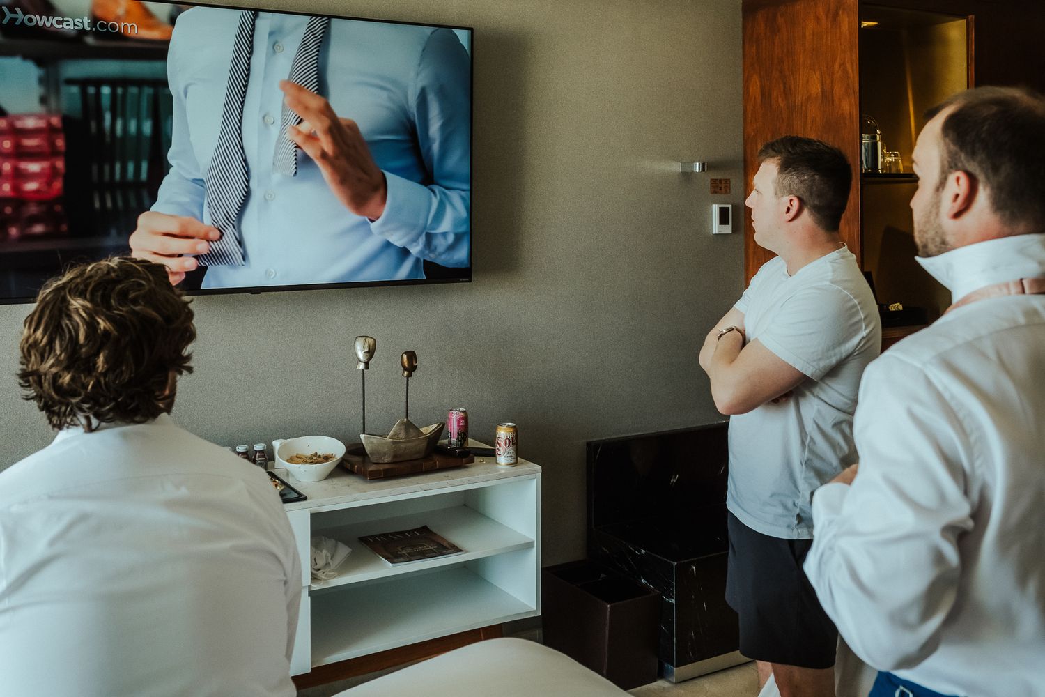 Three people watching a presentation on TV in a living room setting.