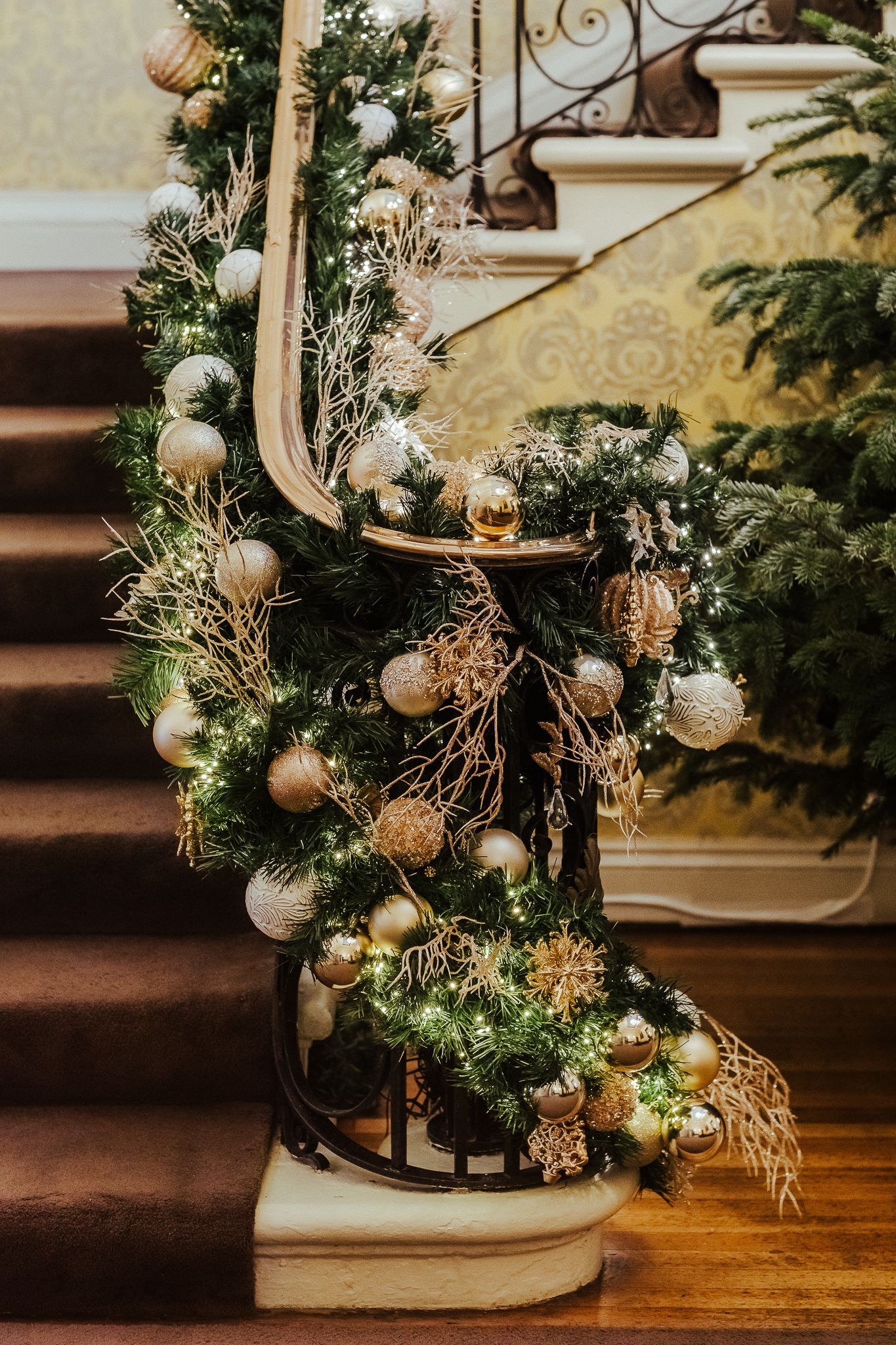 Elegant Christmas decorations with gold ornaments and greenery on wooden stairs.