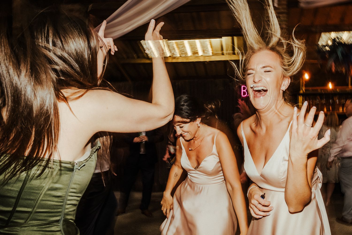 Happy wedding guests dancing and laughing during an energetic reception celebration.
