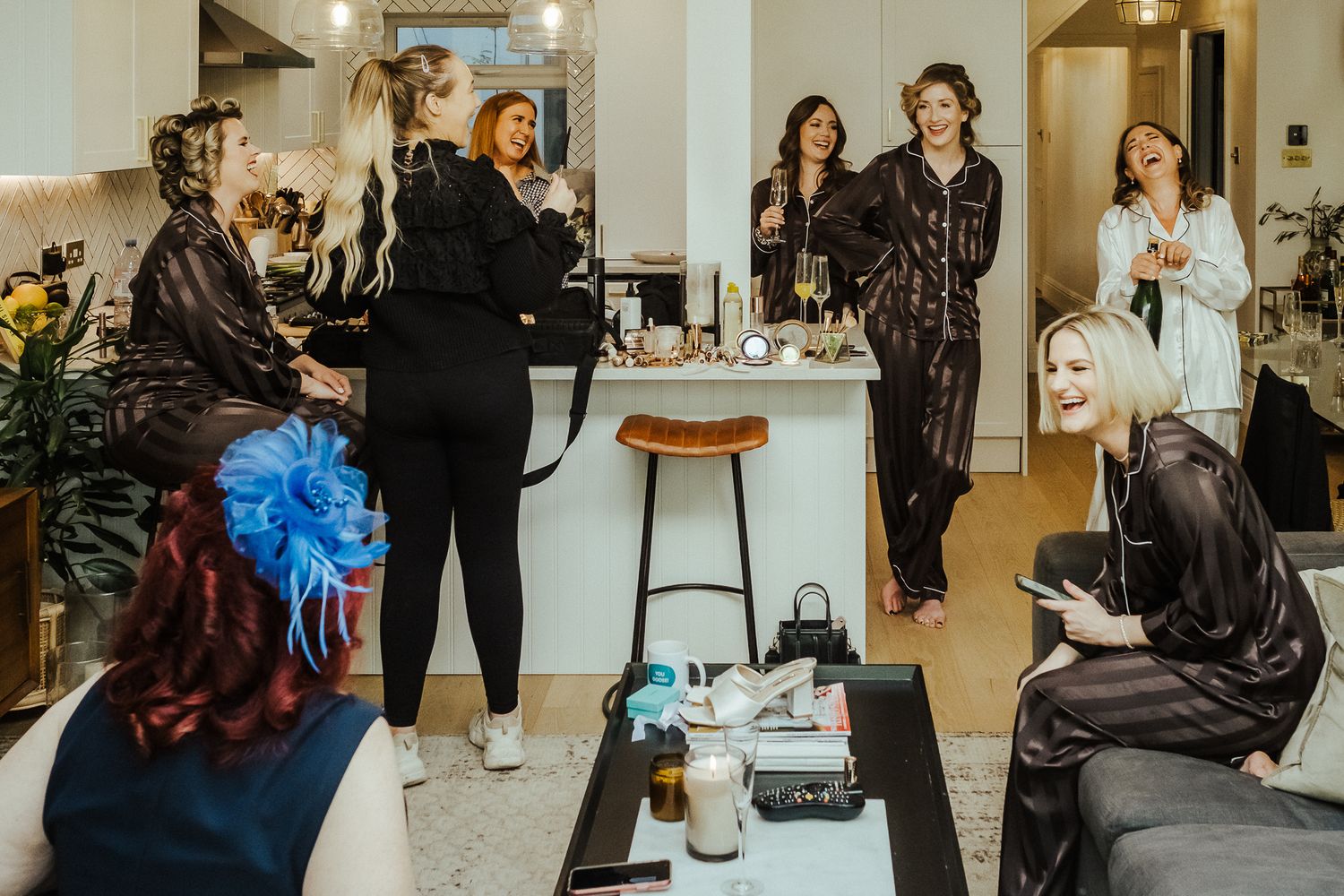 People in a salon preparing for an event with hair and makeup stations visible.