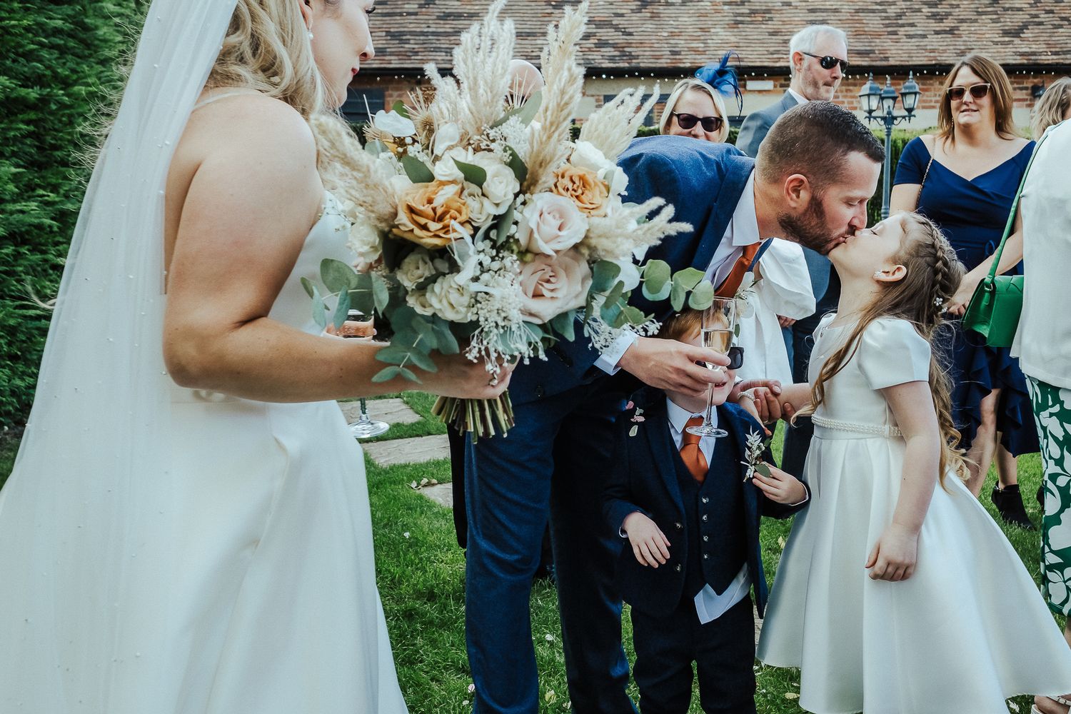 Wedding guests gather outdoors for a joyful celebration in a garden setting.