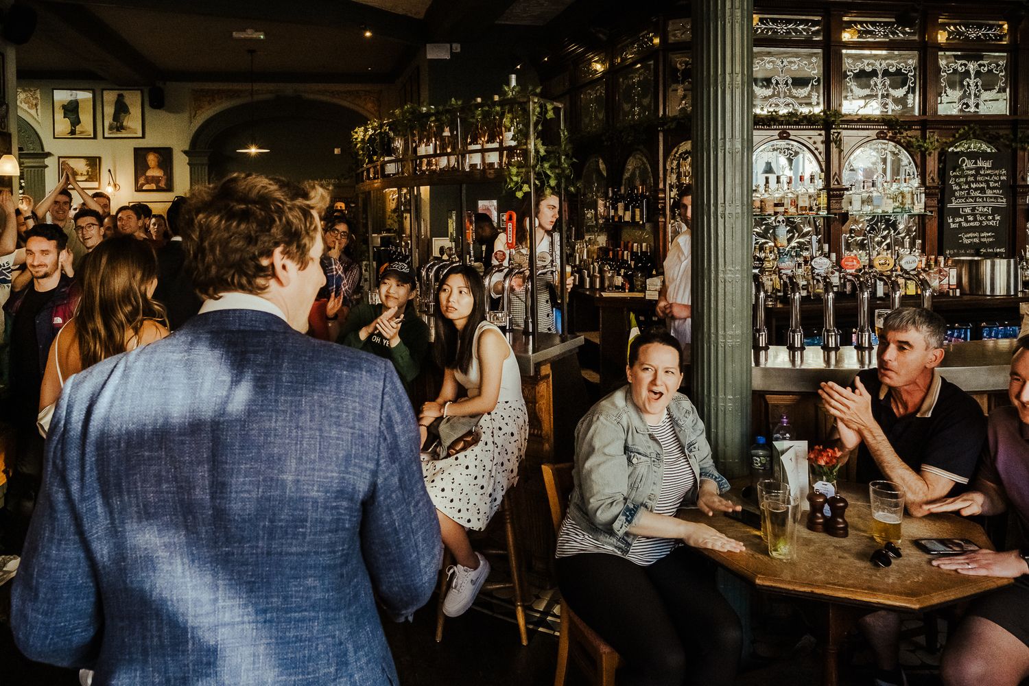 Wedding guests enjoying drinks and conversation in a dimly lit vintage pub interior.