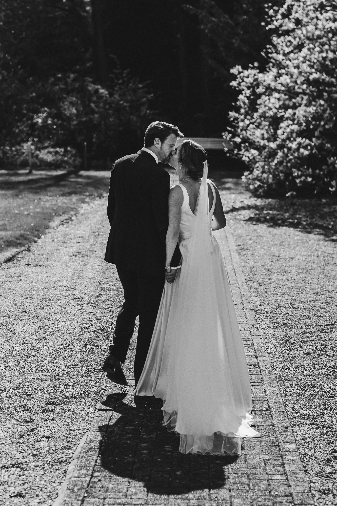 Black and white intimate moment captured on garden path at wedding.