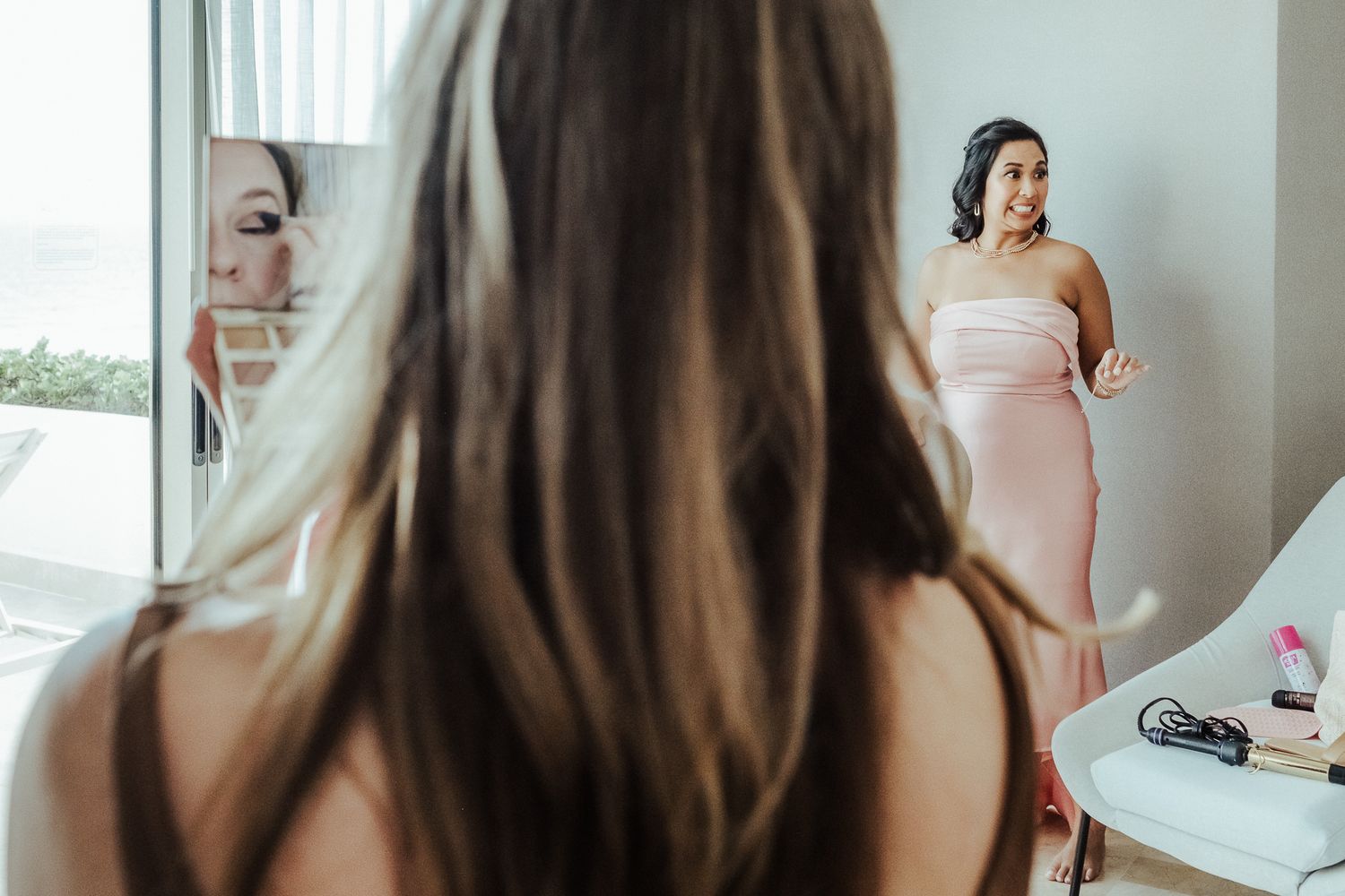Person admiring their reflection in a mirror while wearing a pink dress.