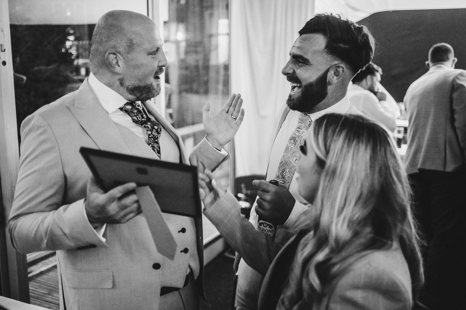 A suited professional engaged in conversation with sports athletes at a formal gathering in black and white.