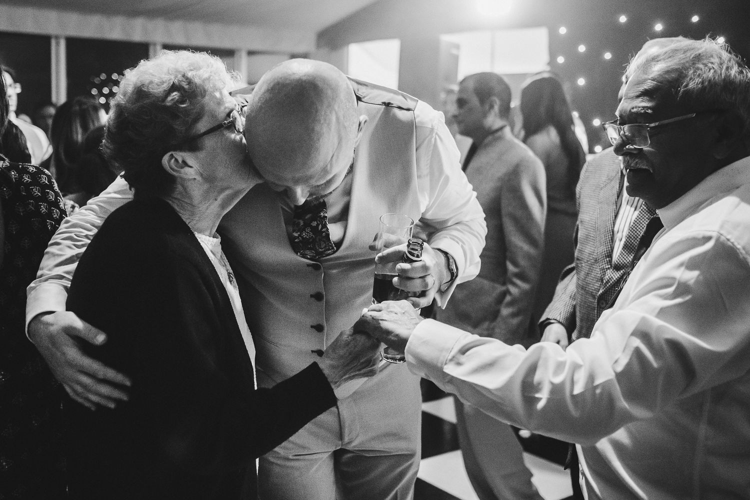 Couples share intimate dance moves on a dimly lit ballroom floor during a wedding reception celebration.