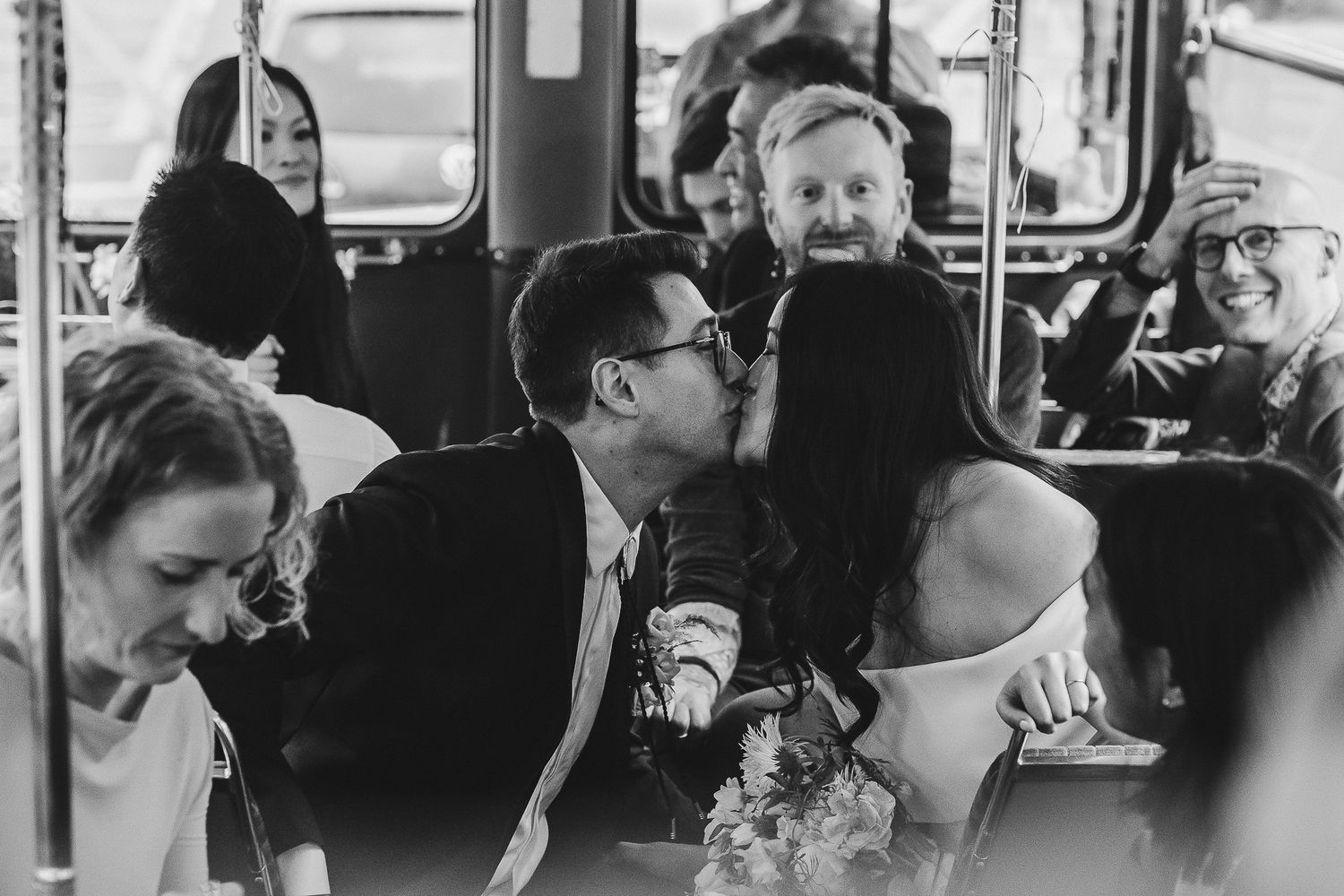 Passengers enjoy cheerful conversation while riding on a crowded public transit bus in black and white.