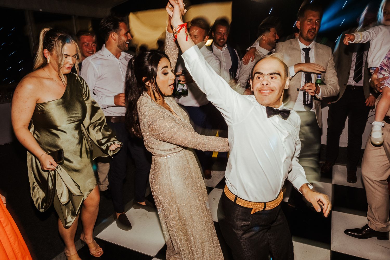 A group of people dancing and having fun at a lively wedding reception party.