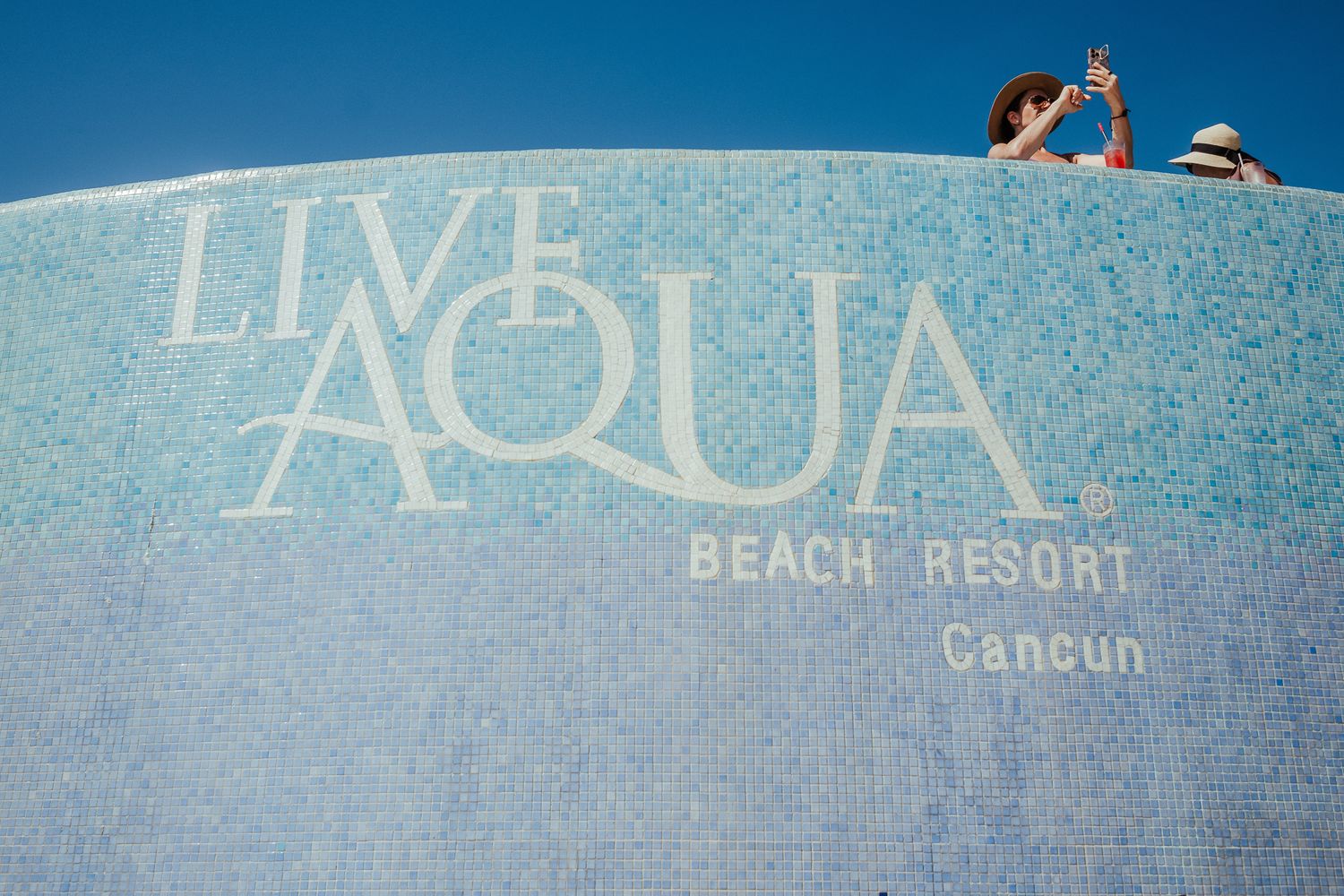 Live Aqua Beach Resort sign in Cancun with bright blue sky background.