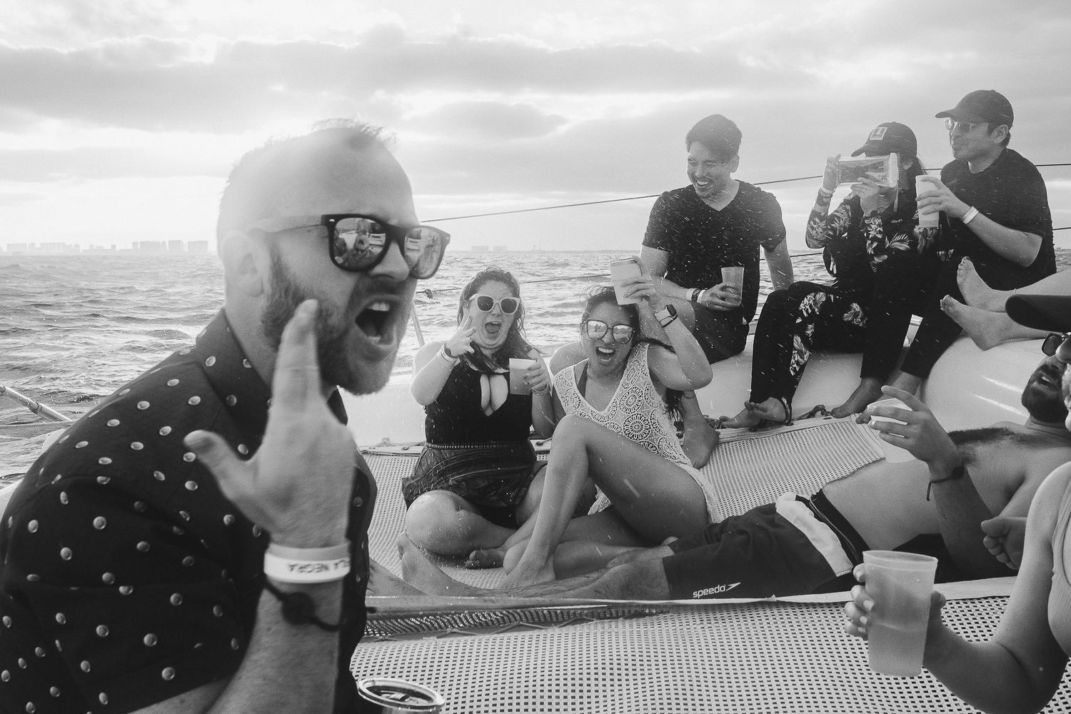 Group of friends socializing and laughing together on a boat deck in black and white.