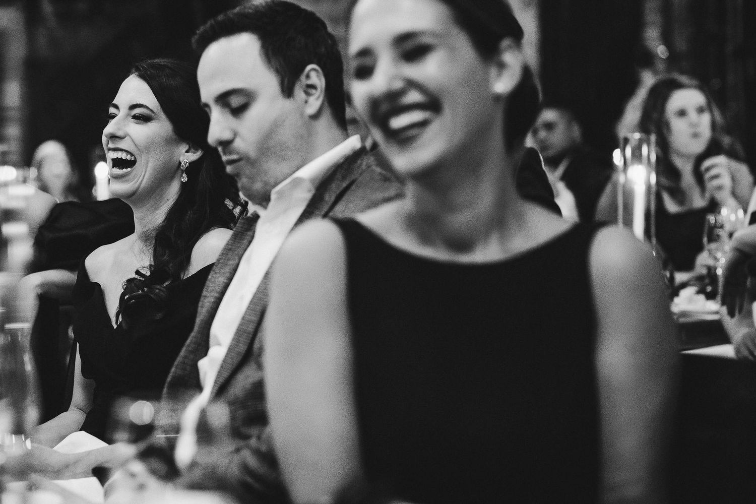 Black and white photo of guests sharing laughter at an elegant dinner party.