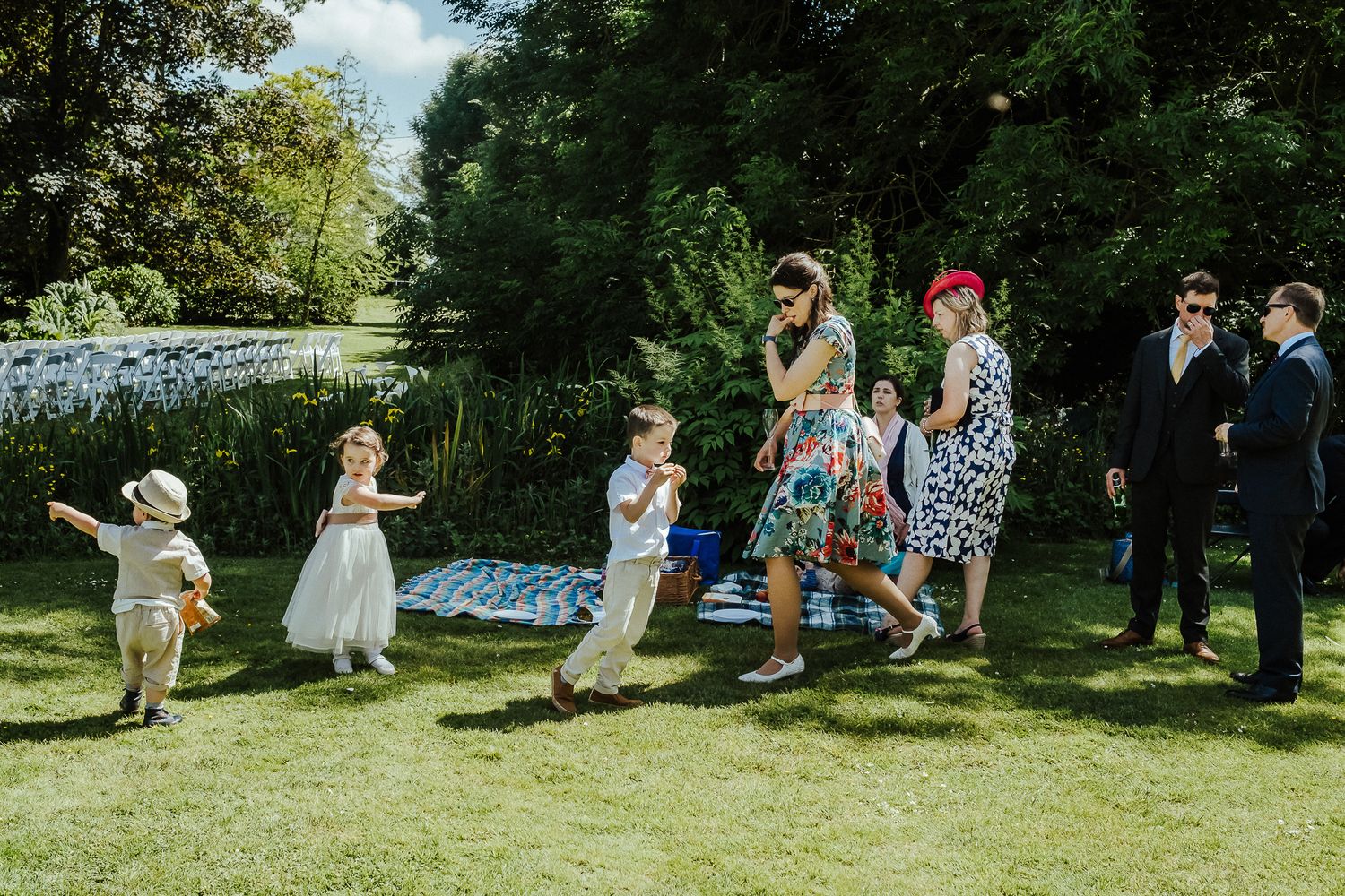 Wedding guests enjoying outdoor festivities on a sunny lawn with decorative elements.