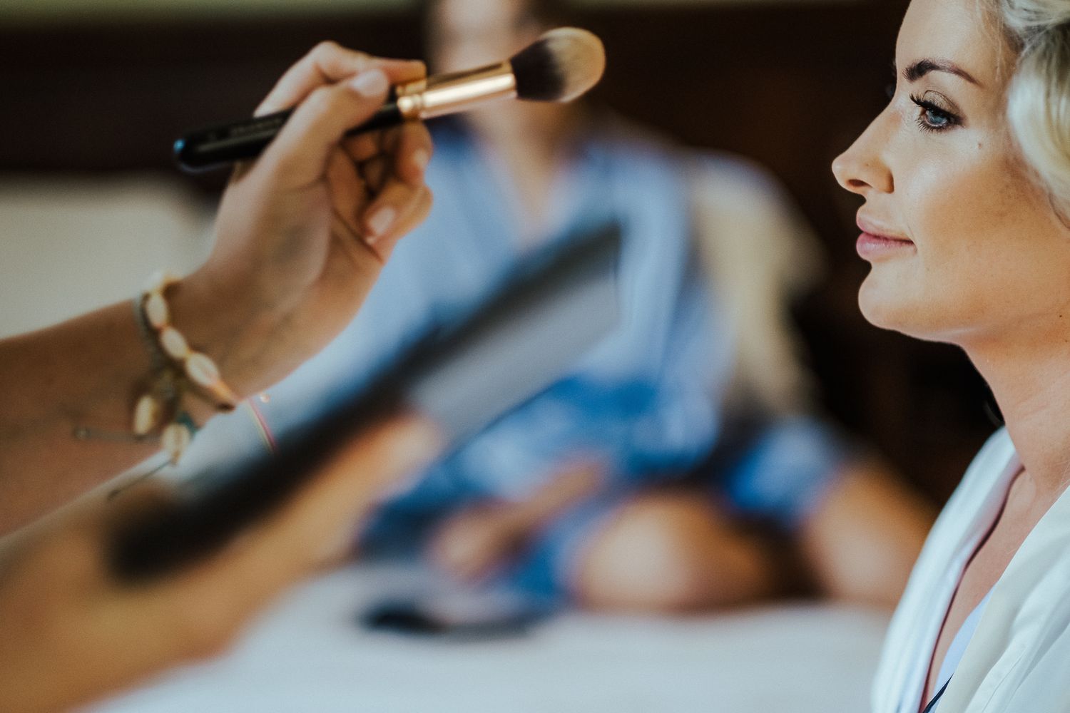 Close-up shot of makeup being applied with a brush in natural lighting.