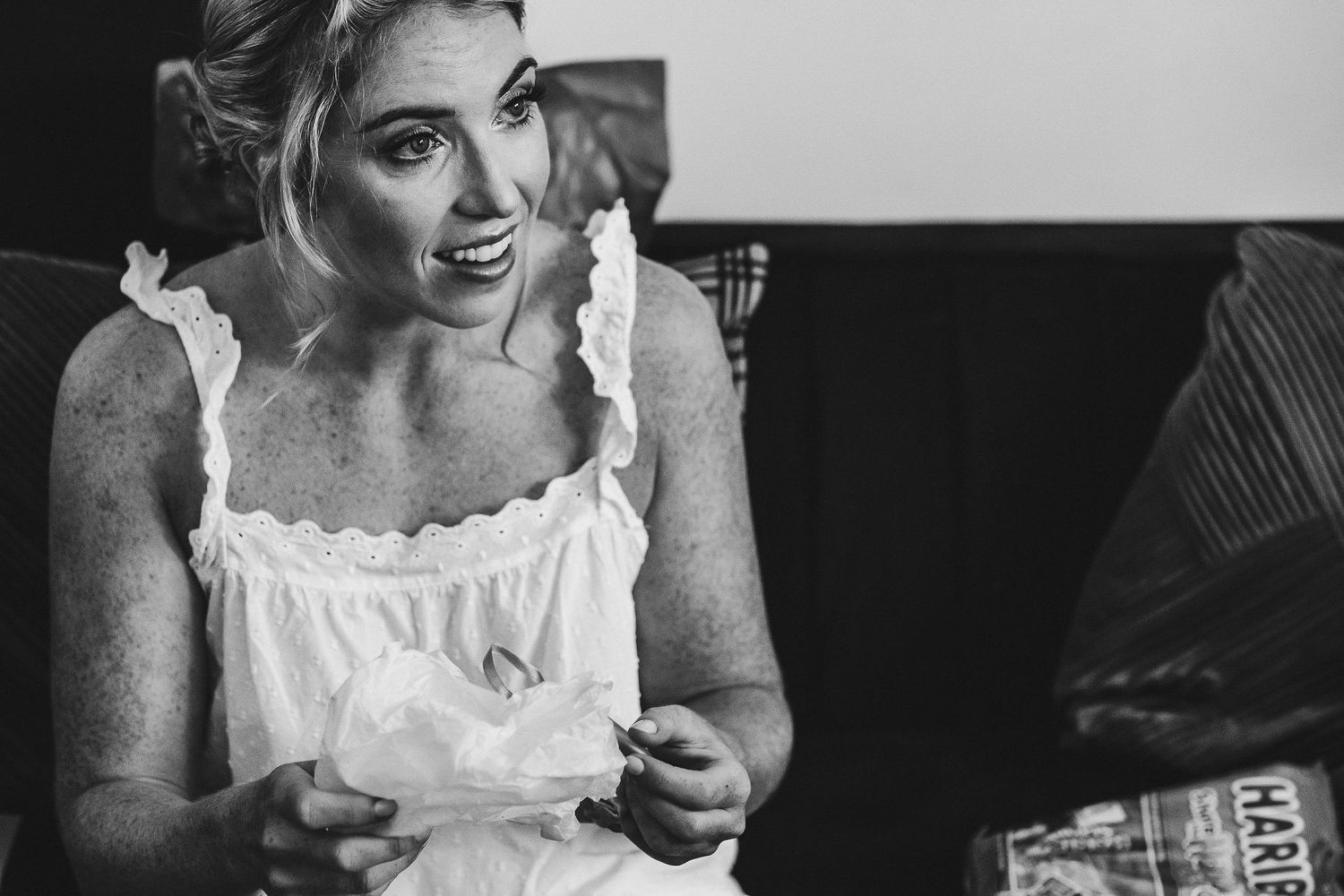 A candid black and white portrait of someone in white during wedding preparations.