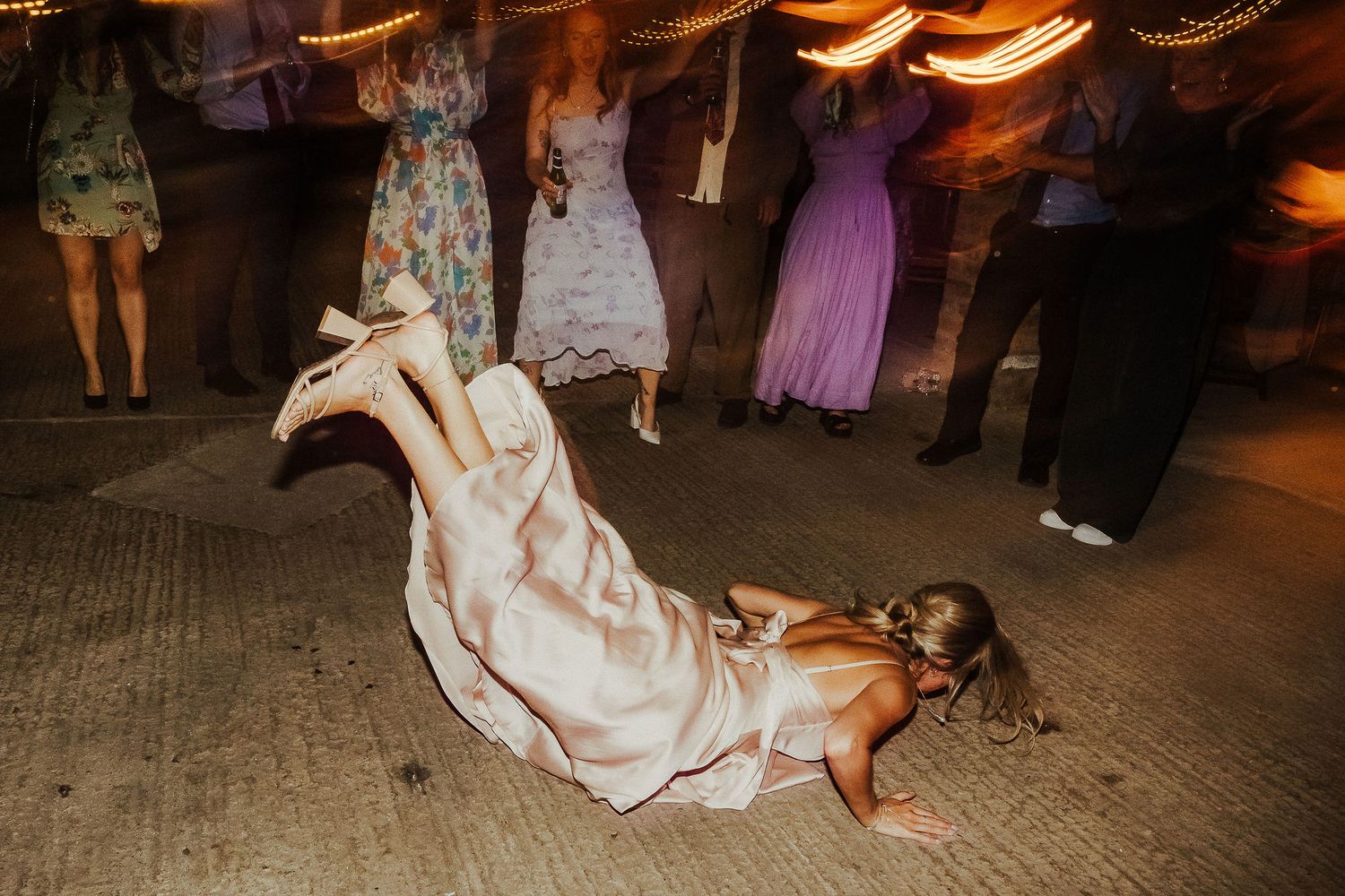 Wedding guest performing a dramatic dance move on the floor during reception.