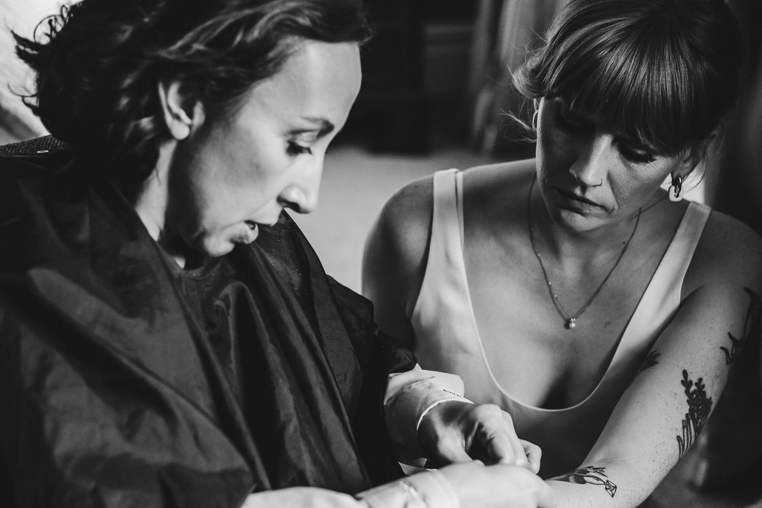 Black and white photo of wedding preparations with two people in intimate discussion.