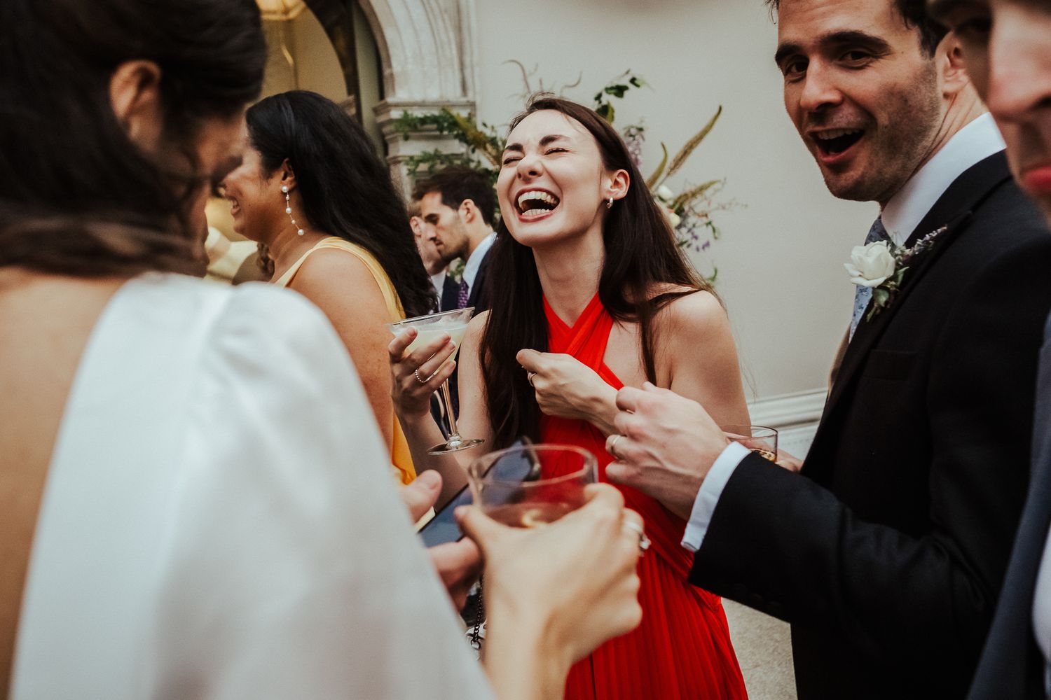 Wedding guests sharing drinks and laughter during reception celebration.