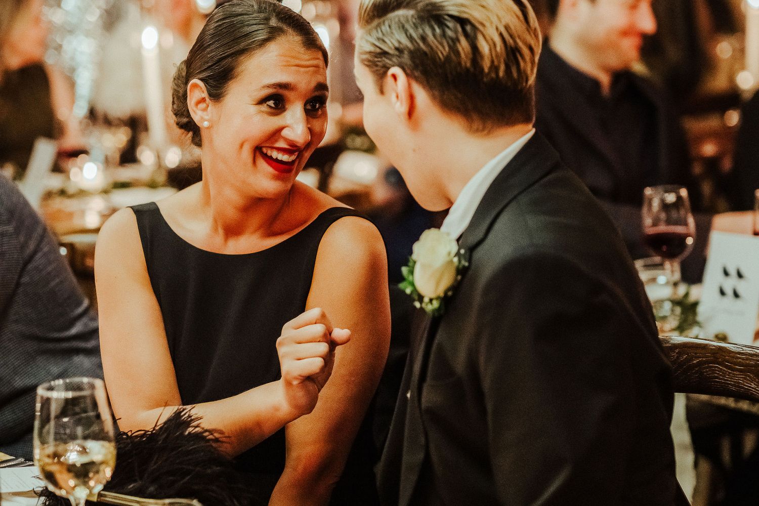Guests dressed in formal attire share intimate conversations at a dimly lit event.