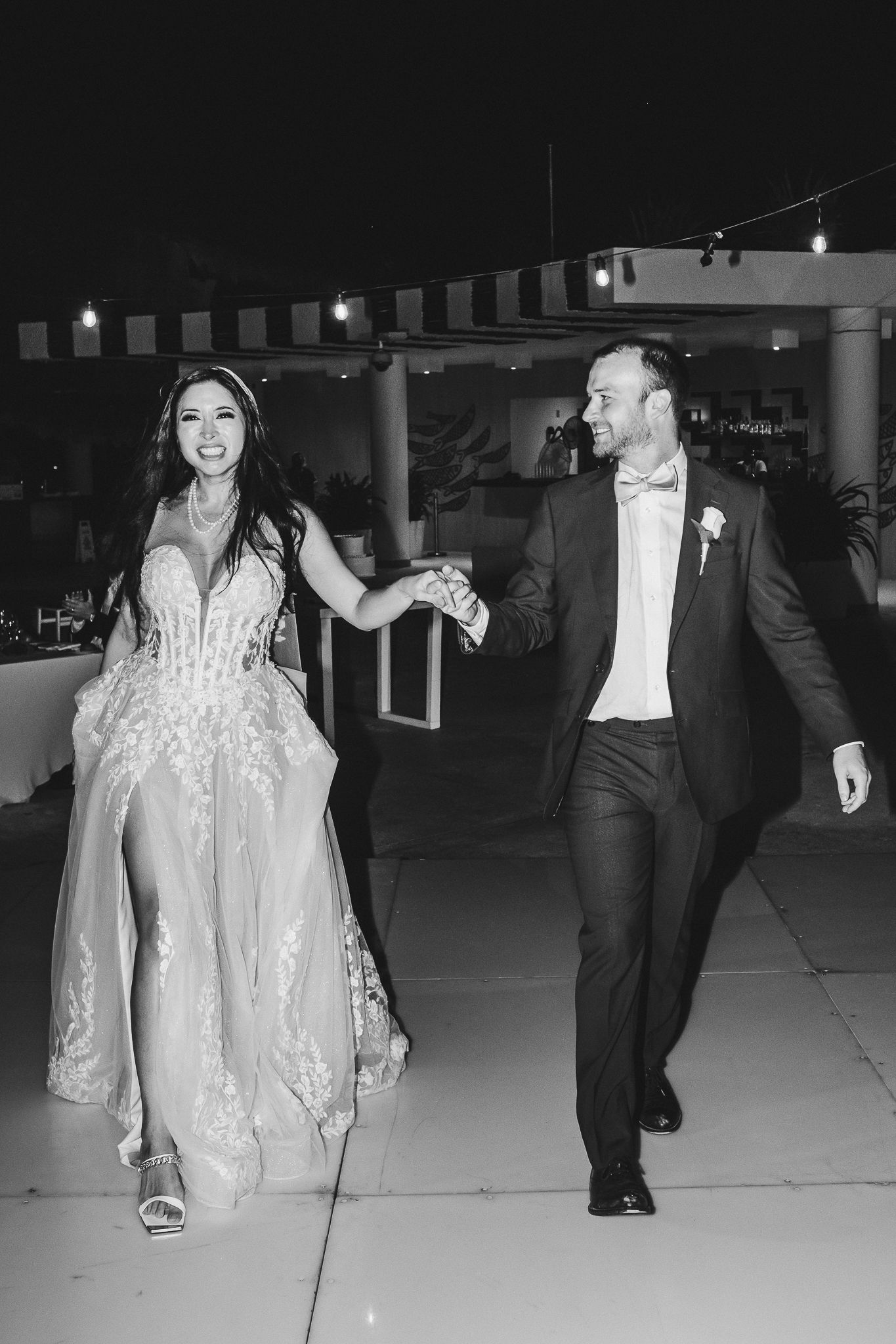 A couple dances together at their wedding reception under string lights.