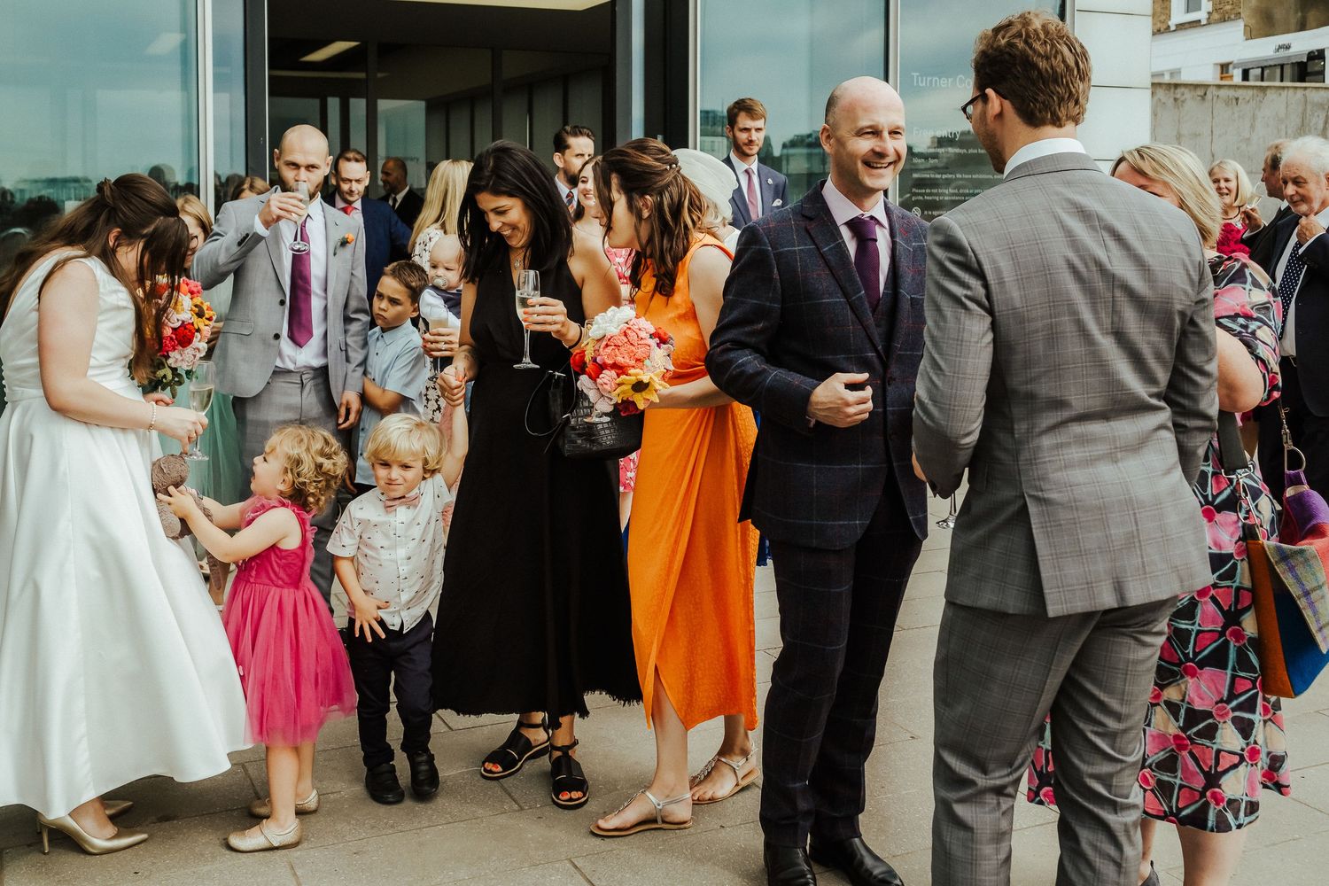 Guests in vibrant attire mingle during an outdoor wedding celebration.