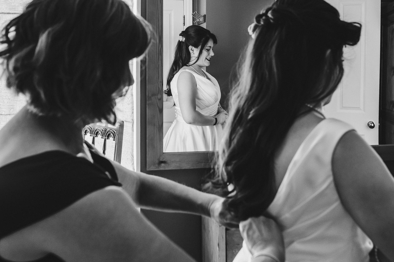 Black and white image showing pre-wedding preparations reflected in a mirror.