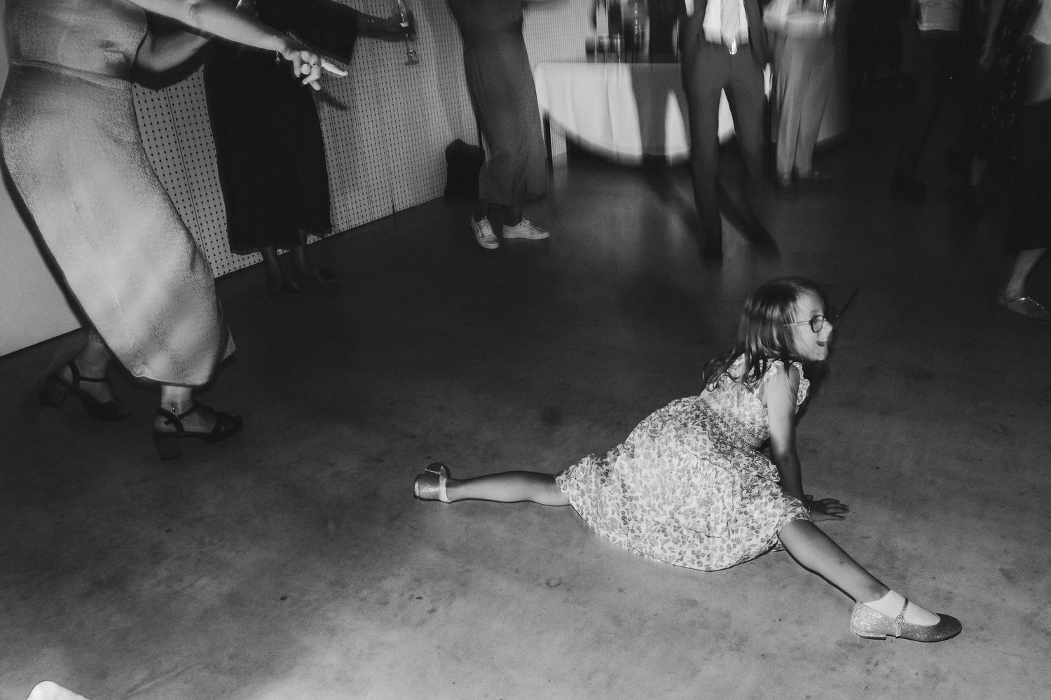 Person in polka dot dress performs dramatic split move on dance floor.