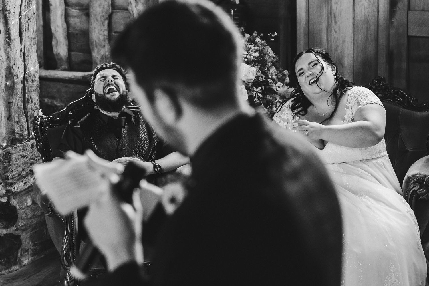 Wedding party erupts in joyous laughter during outdoor celebration.
