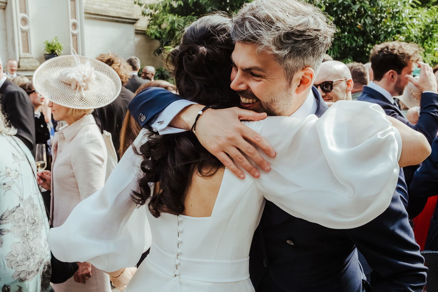 Cheerful wedding celebration with guests embracing and toasting outdoors.