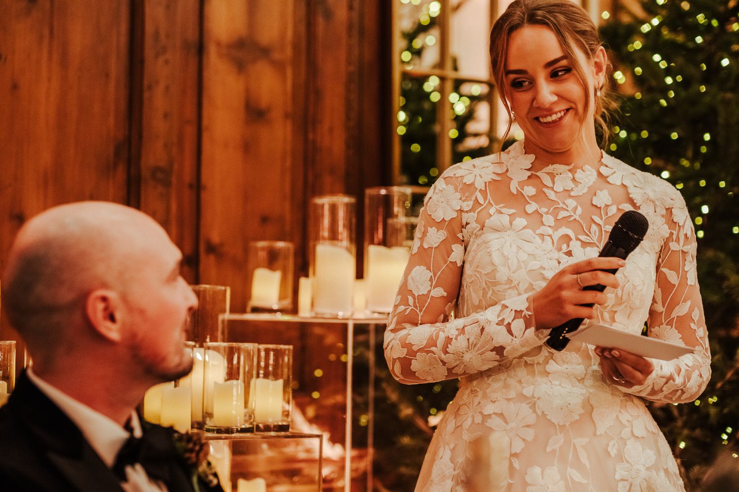 Wedding couple sharing emotional moment during reception speech with Christmas decorations in background.
