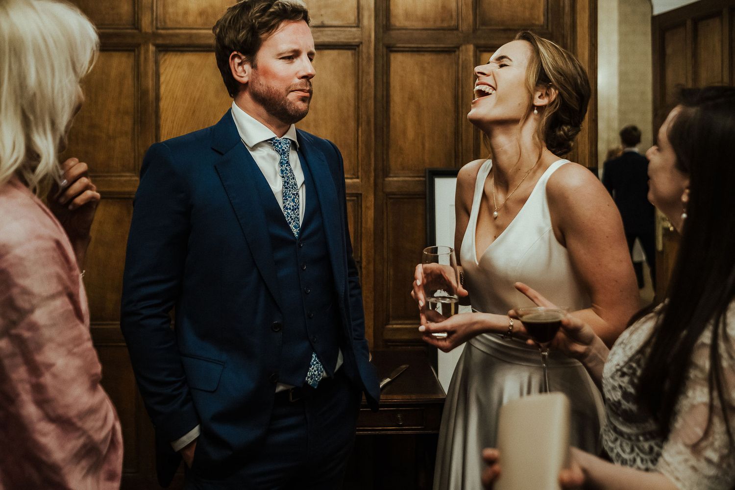 Intimate moments shared between guests at an elegant wood-paneled reception venue.
