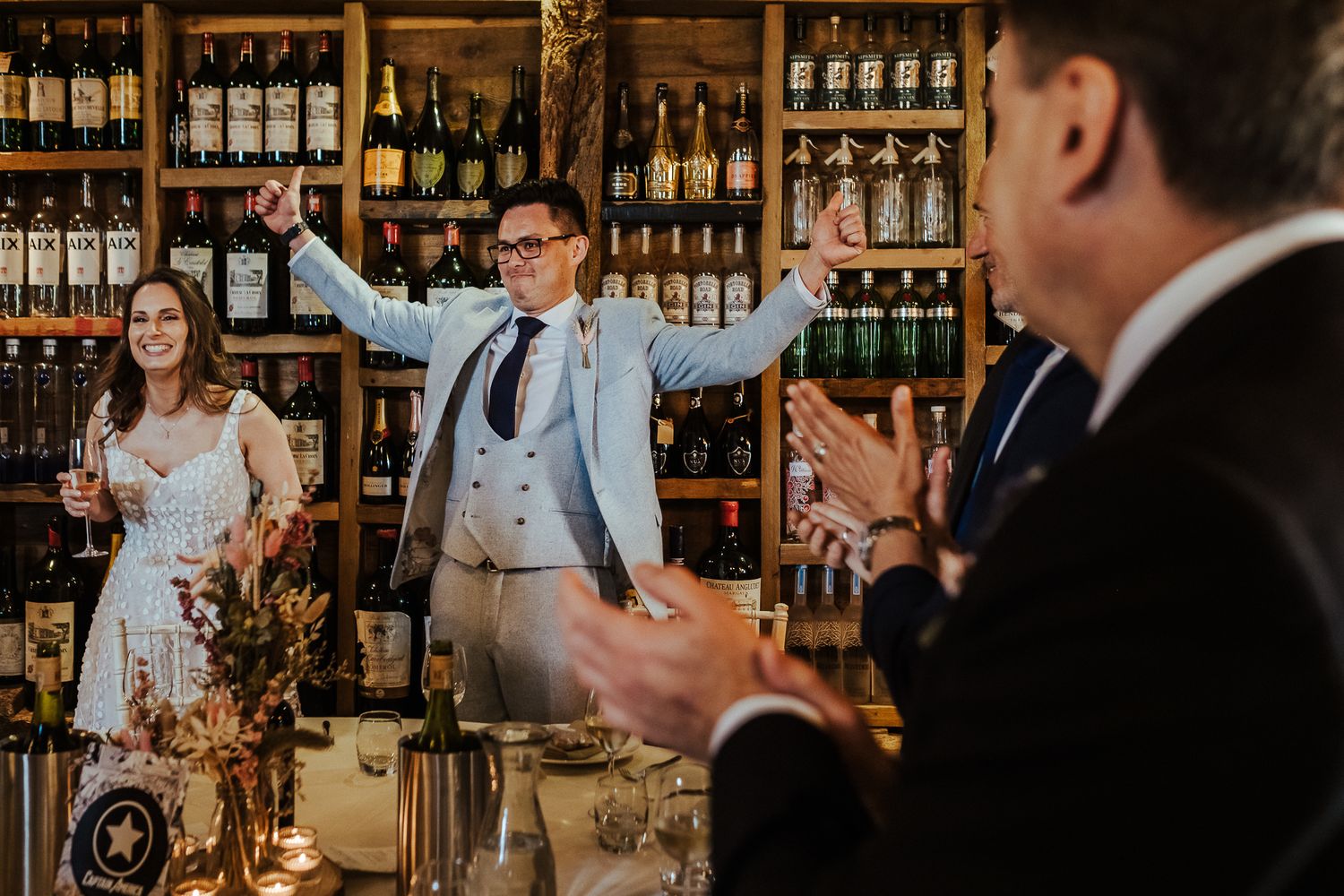Wedding celebration in rustic wine cellar with guests applauding.
