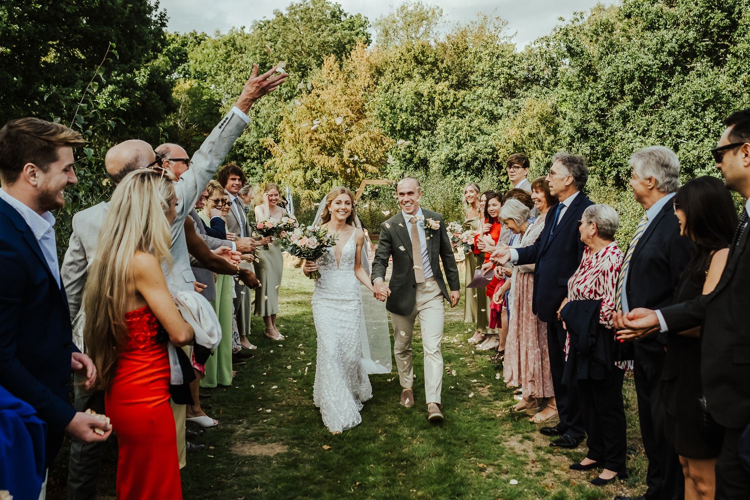 Guests form aisle for newlyweds' exit walkway at outdoor wedding ceremony.