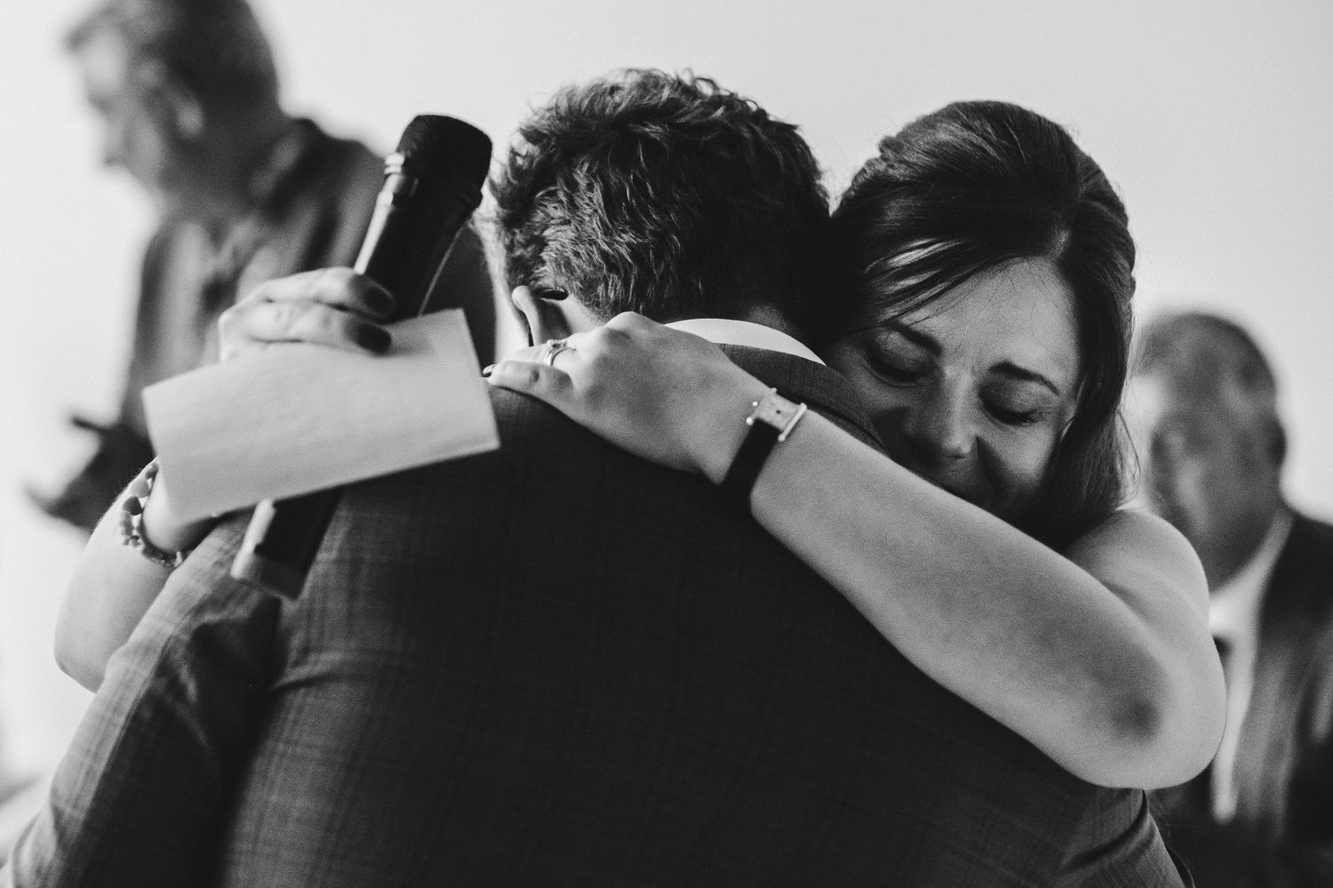 A tender black and white moment captured during an emotional embrace at a wedding reception.