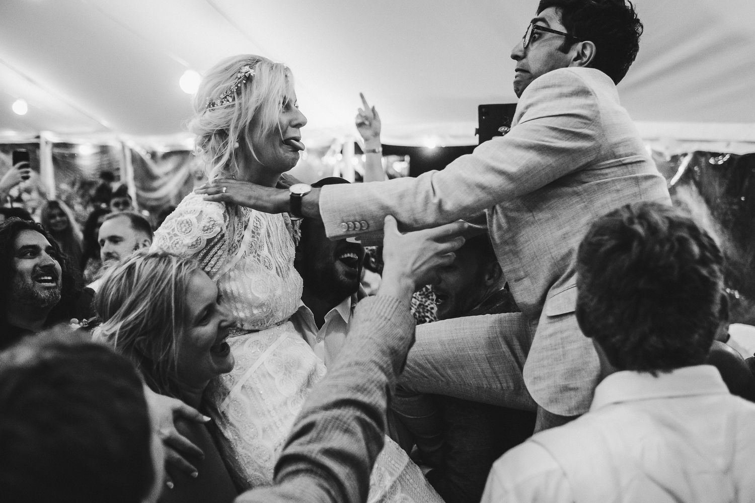 Wedding guests celebrate and dance energetically at a lively reception party.