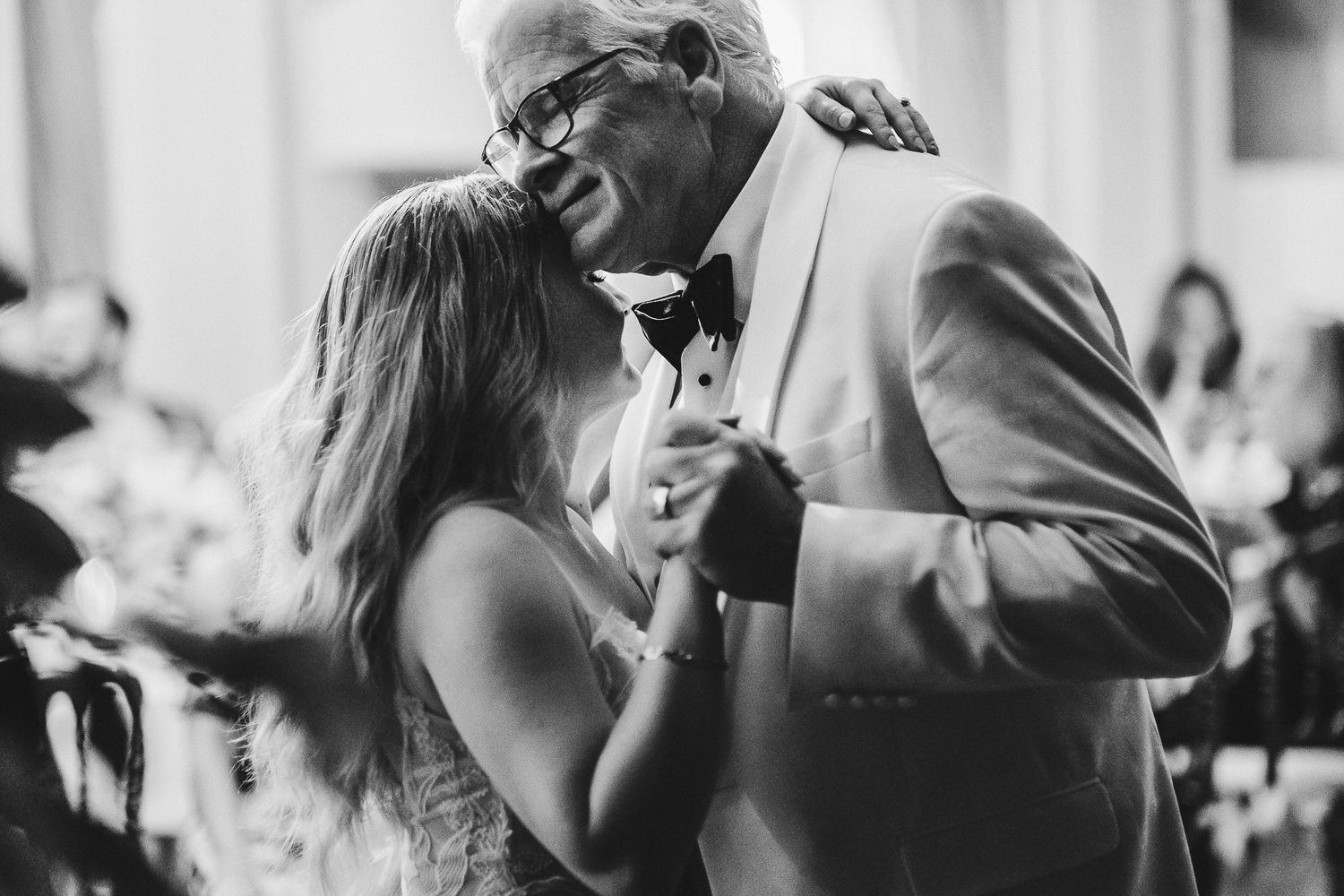 Tender moment of a couple dancing together at a wedding reception in black and white.