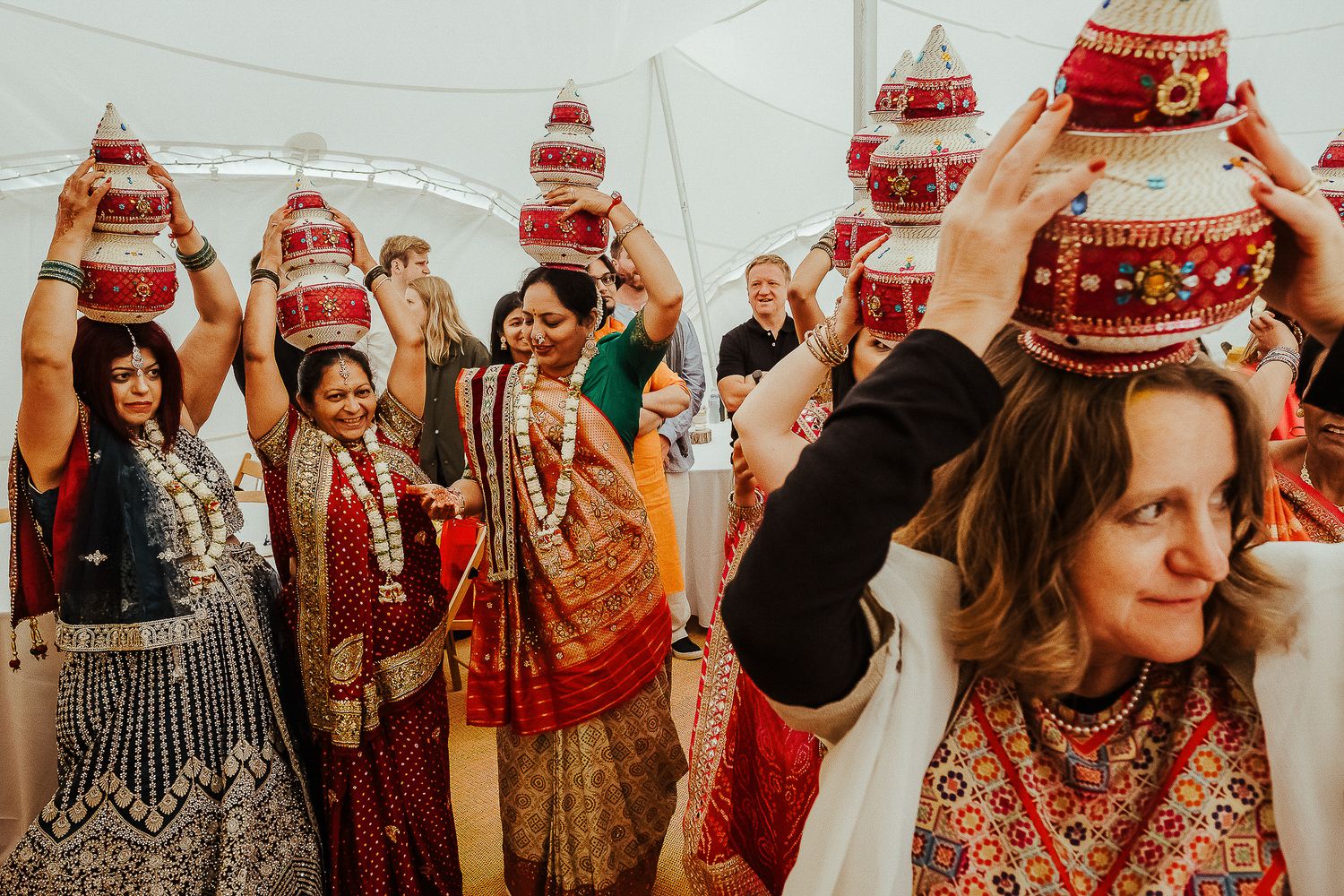 Group celebrating with traditional red kalash decorations at a cultural ceremony.