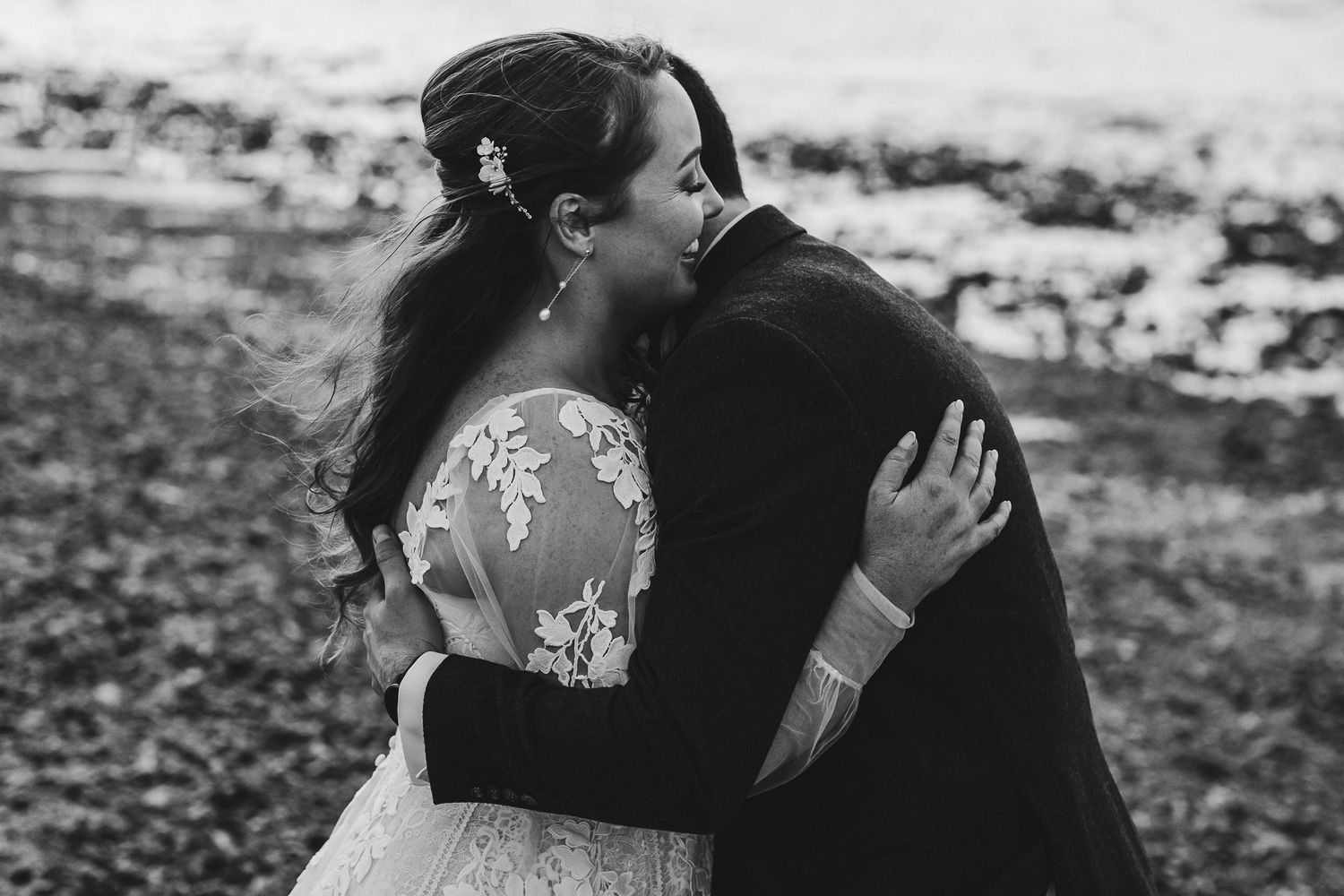 A romantic black and white wedding photo showing an intimate embrace between newlyweds against a blurred backdrop.