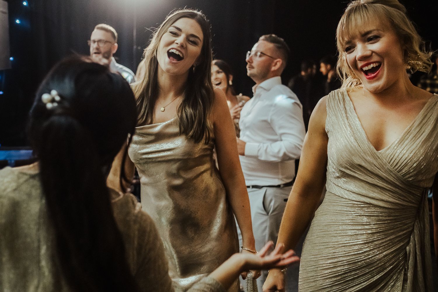 Wedding party guests dancing and laughing together on the dance floor during reception celebration.
