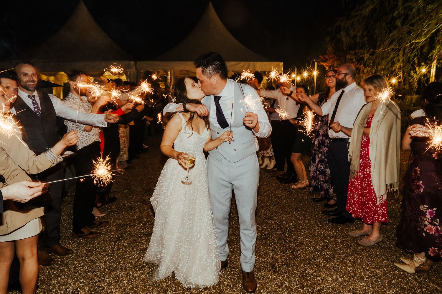 Newlyweds dancing through a sparkler exit lined with wedding guests.