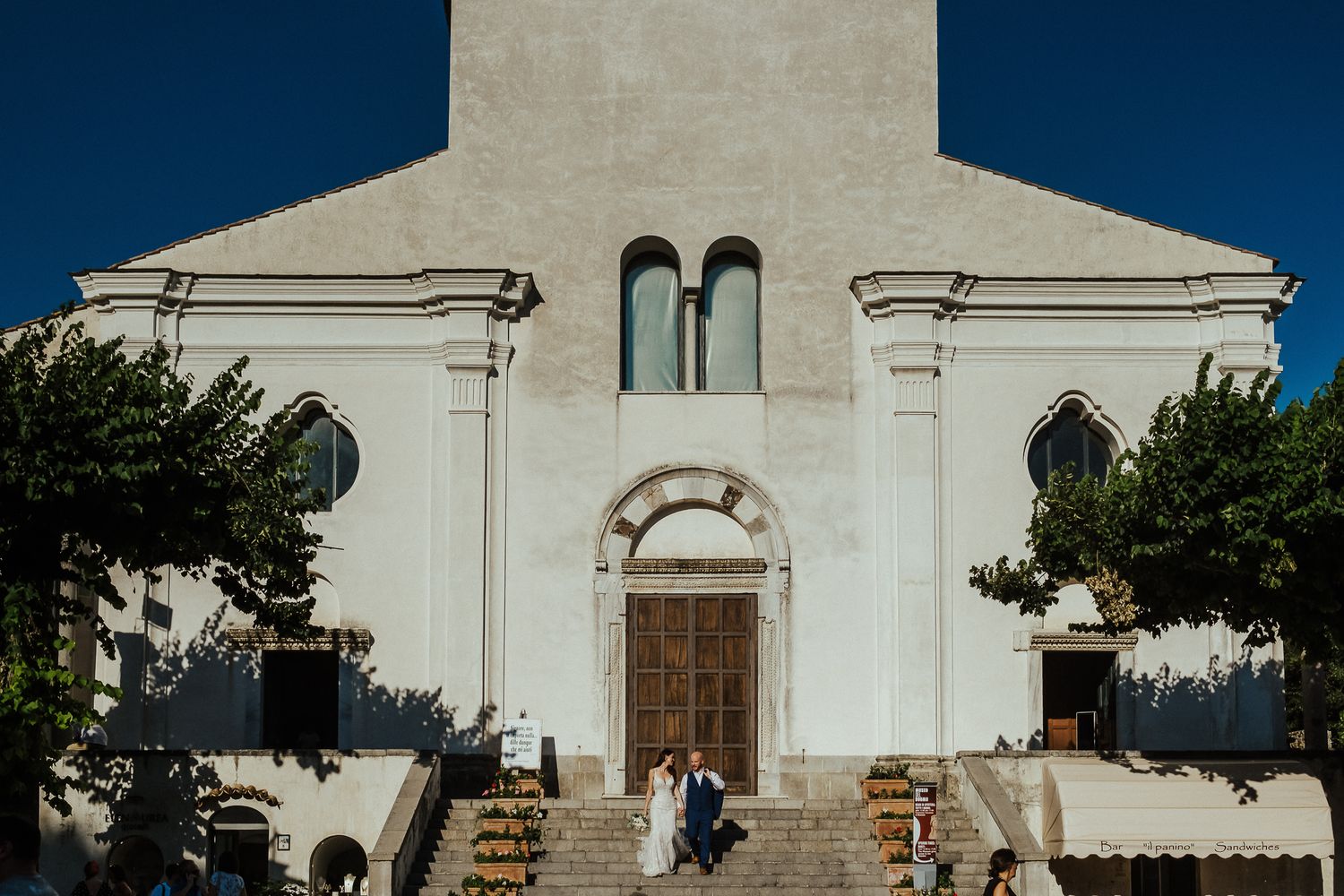 A grand white church entrance with stone steps and arched doorways against a deep blue sky.