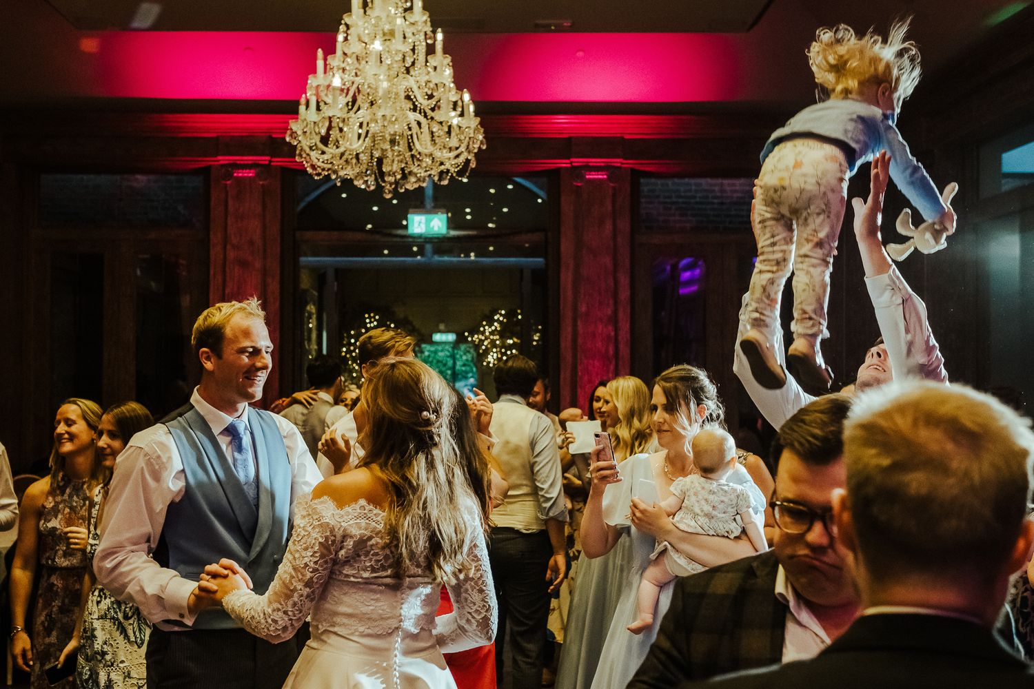Energetic dance floor scene with chandelier and guests celebrating at an elegant reception.