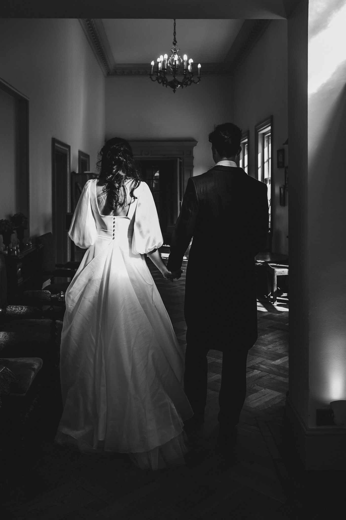 Dramatic black and white wedding photographs in a hallway setting.