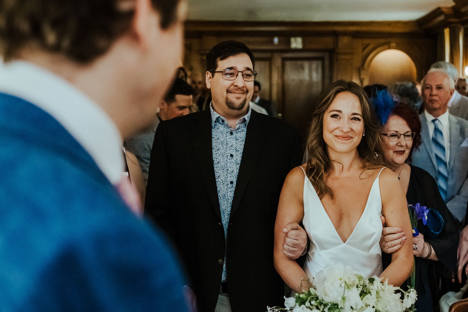 An intimate indoor wedding ceremony with guests watching the couple exchange vows.