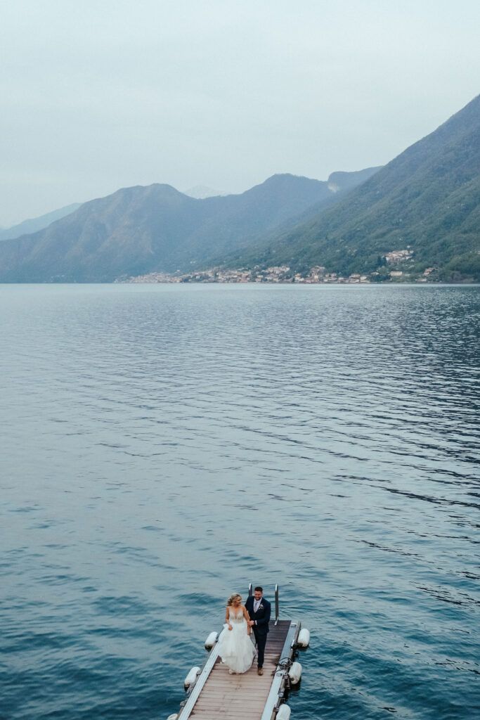 A couple exploring a scenic mountain lake vista while standing on a wooden dock.