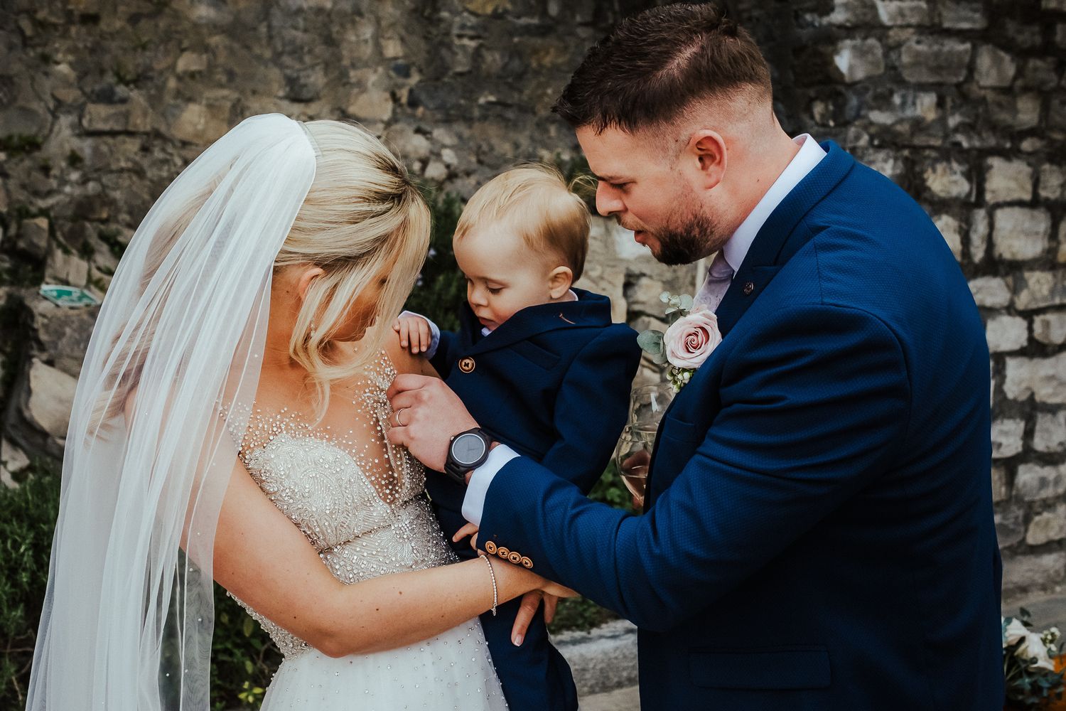 A tender family moment at a wedding with a small child touching the bride's face as they share a sweet interaction.