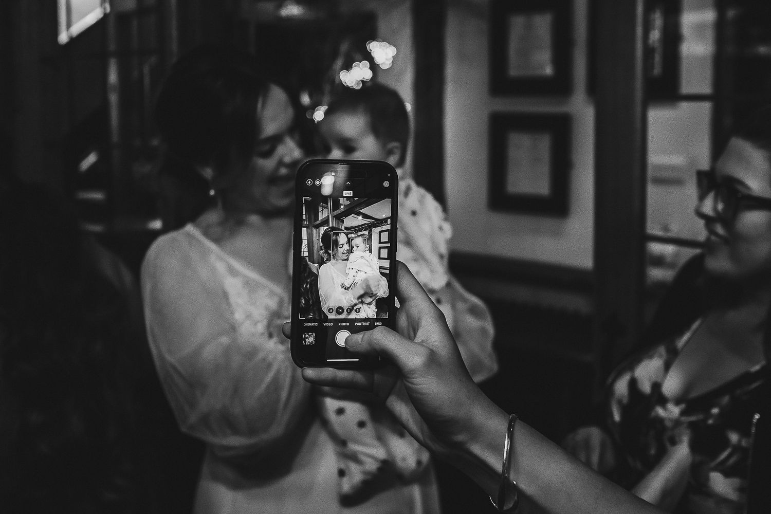 Atmospheric black and white photo of wedding guests taking pictures with mobile phones.